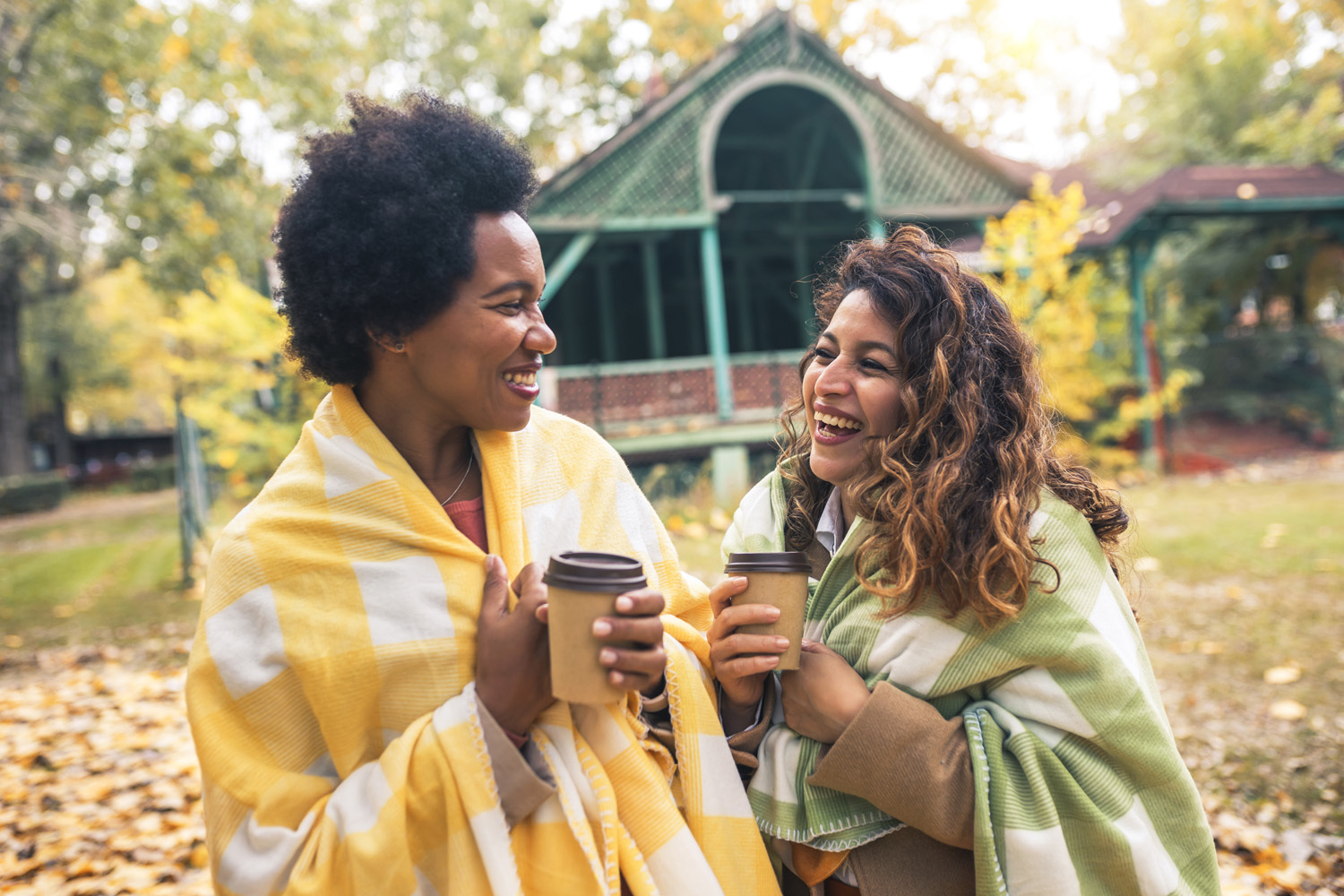 Laughing women enjoying coffee in autumnal park