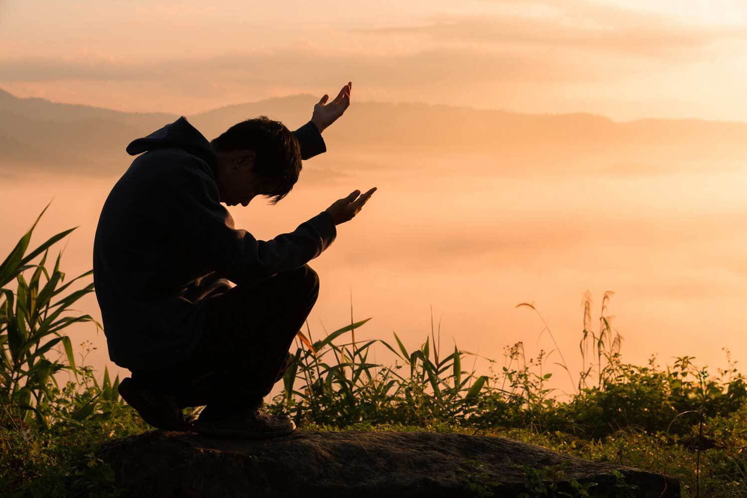 Man praying at sunset