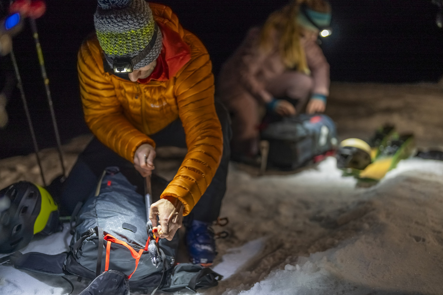 Mountaineers packing rucksacks by headtorch