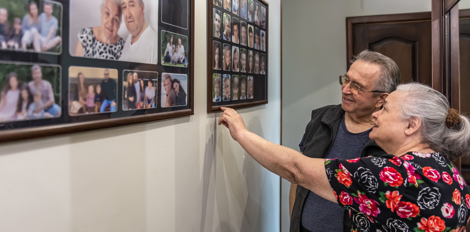 Older man and woman with family photos on wall