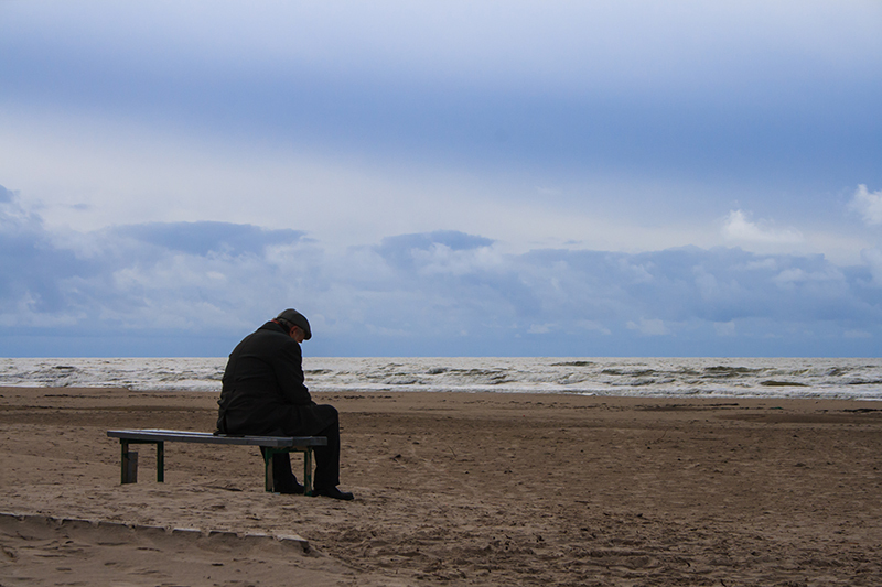 Sad man sitting alone on beach