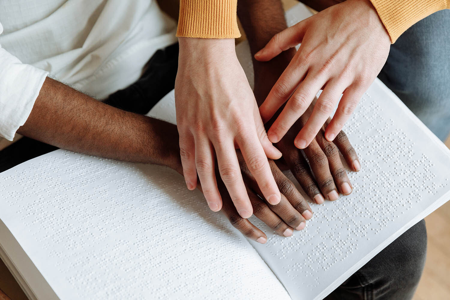 Two pairs of hands reading braille