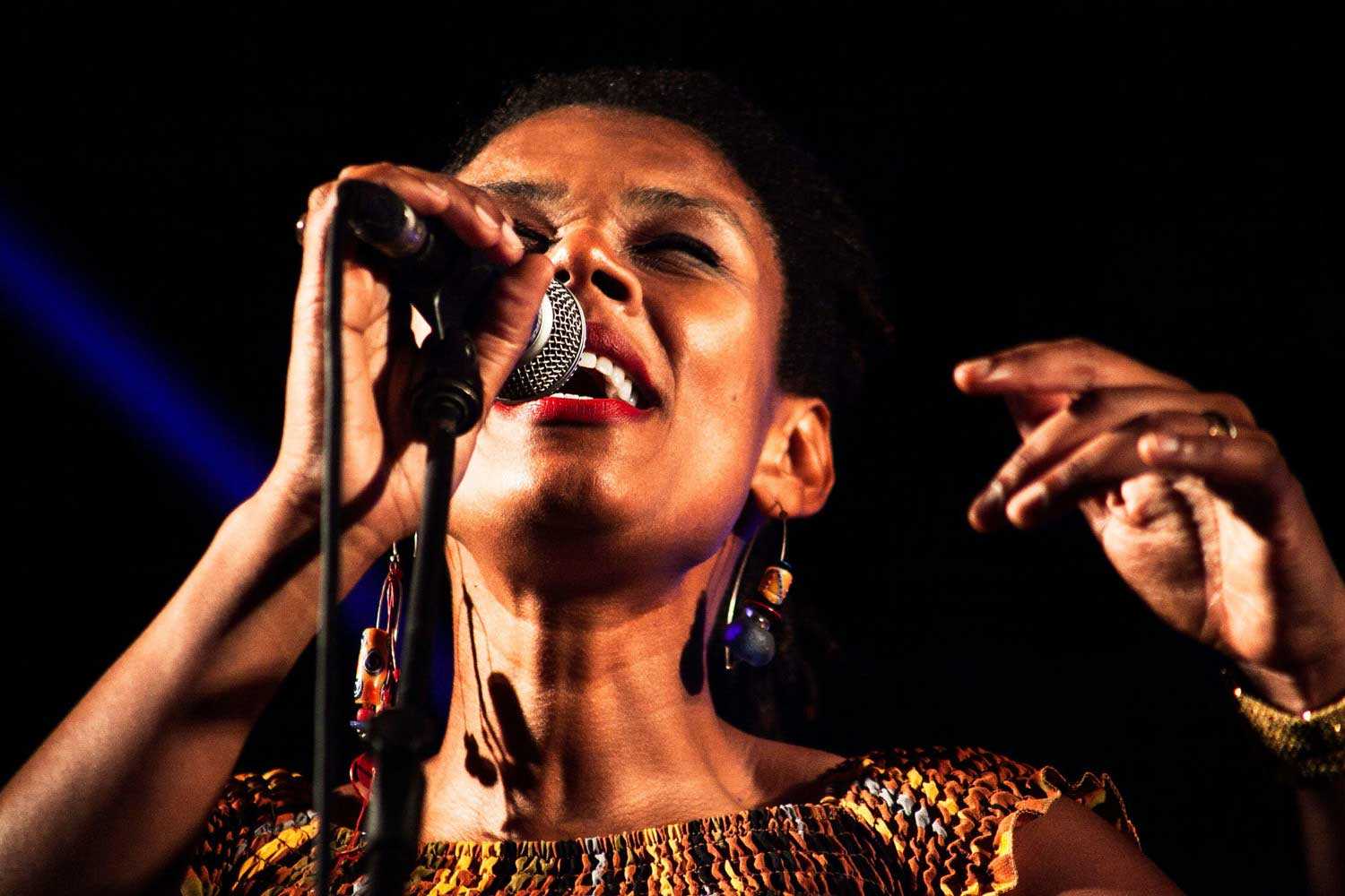 Woman singing into microphone on stage 1500px